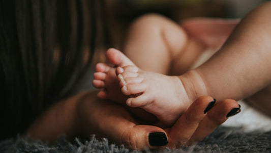 Mutter hält liebevoll die Füße ihres Neugeborenes – dank Embrynatal Forte.